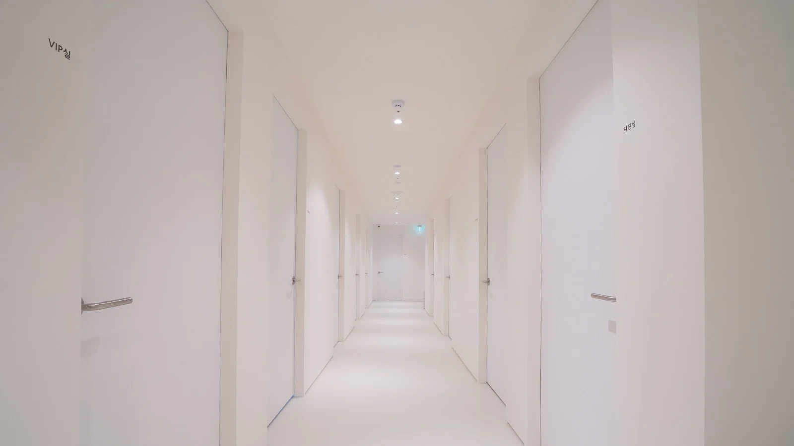 Minimalist white hallway with doors at 345 Plastic Surgery clinic where natural results are the goal